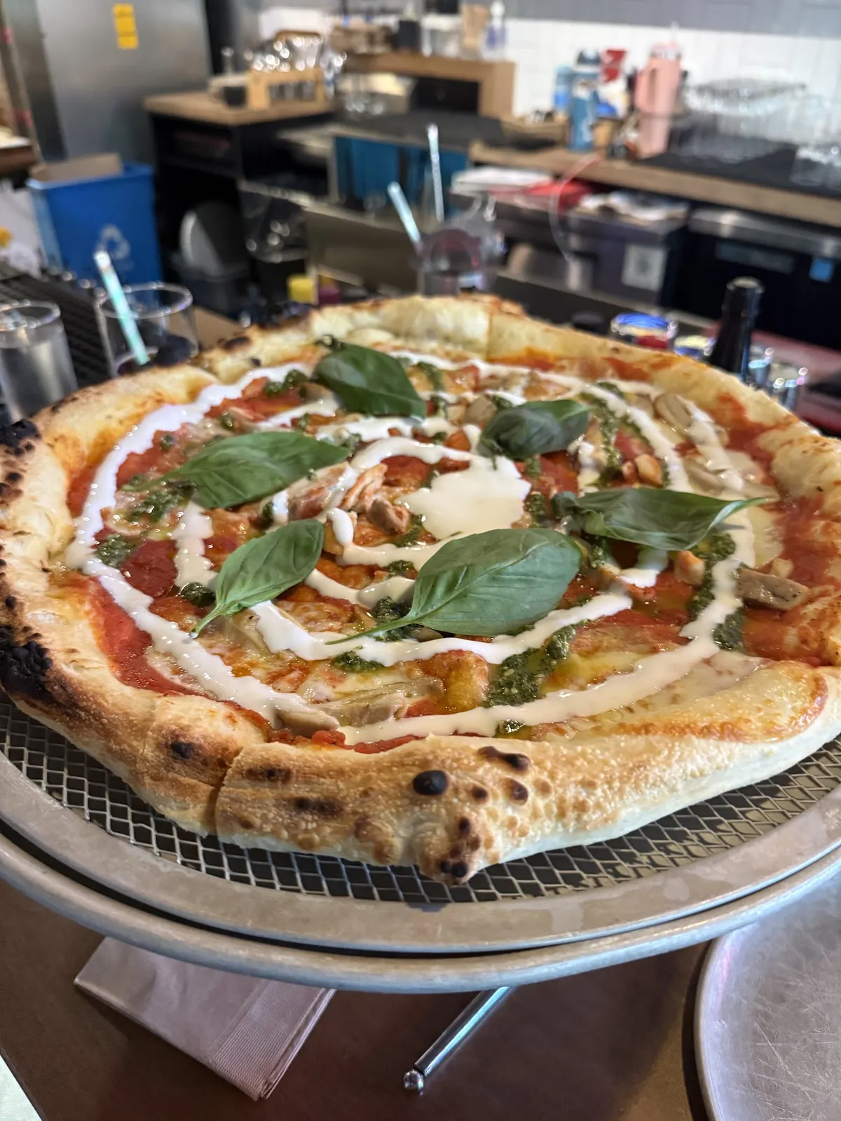 Pizza with basil, pesto, and white sauce