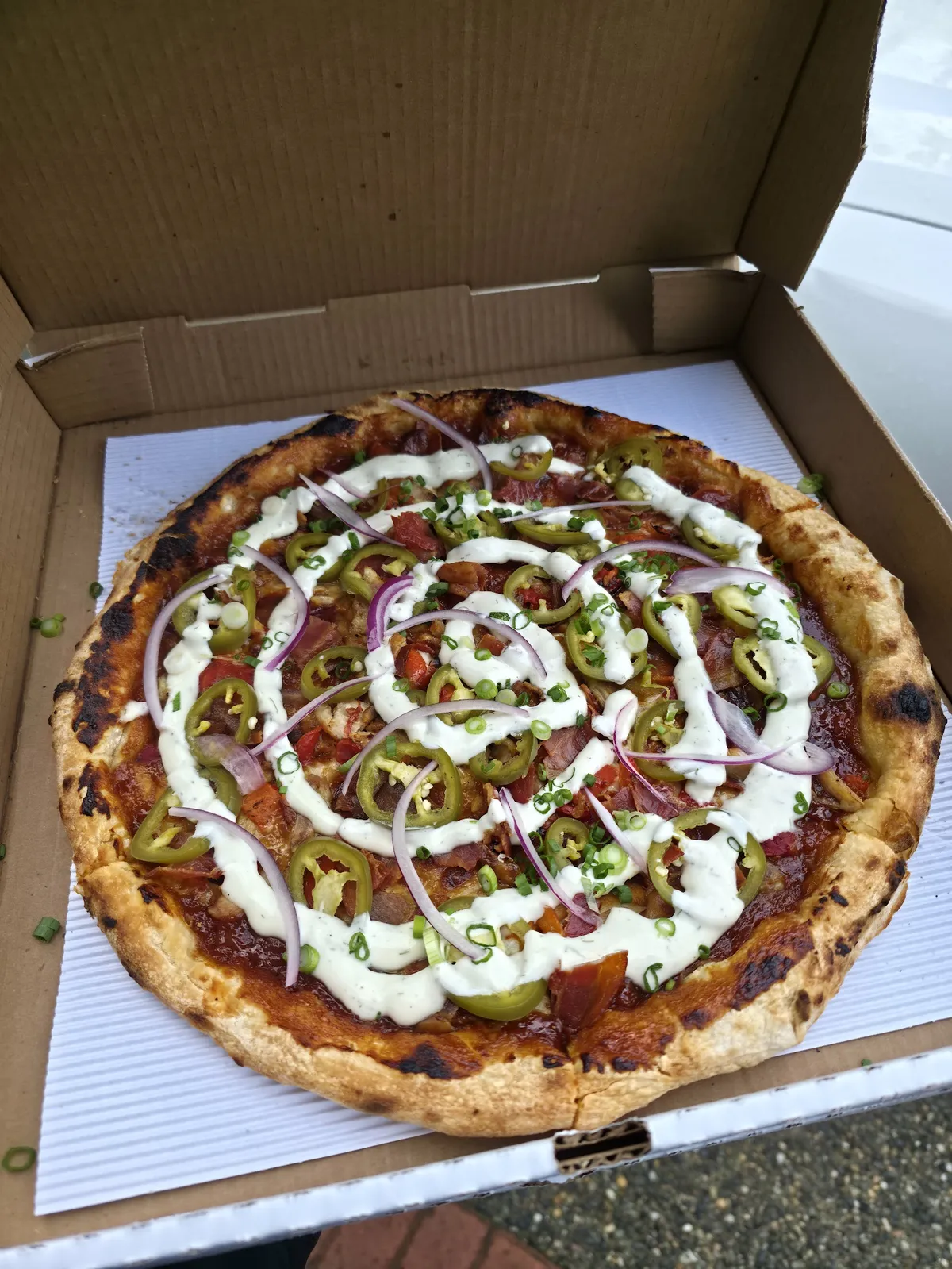 Pizza with various toppings and sauce in a cardboard box
